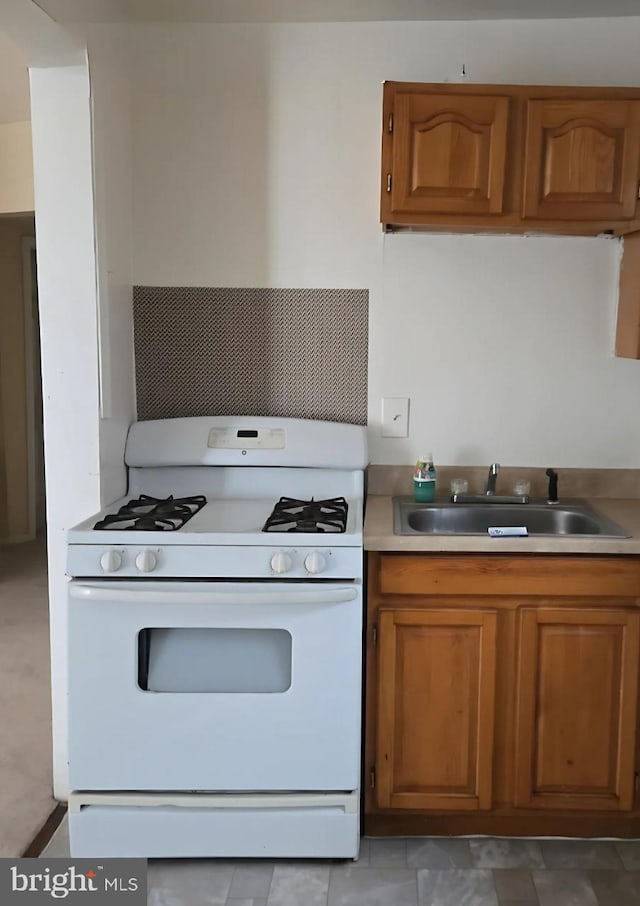 3800 Potee St, Baltimore, MD 21225 - kitchen with white gas range, a sink, brown cabinetry, and light countertops
