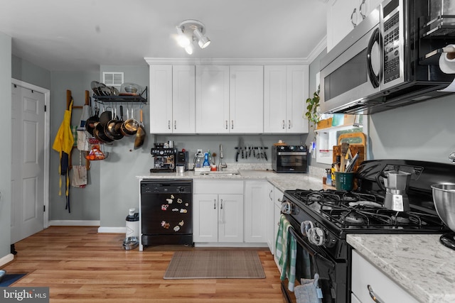 6807 Radcliffe Dr, Alexandria, VA 22307 - kitchen featuring black appliances, a sink, white cabinetry, and light wood-style flooring