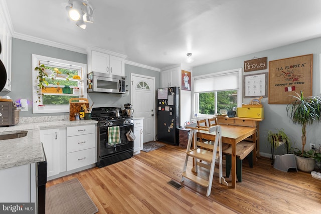 6807 Radcliffe Dr, Alexandria, VA 22307 - kitchen featuring stainless steel microwave, black gas stove, freestanding refrigerator, white cabinetry, and light wood-style floors