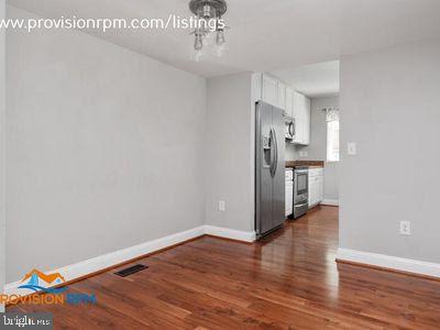 1324 Hazel Nut Ct, Annapolis, MD 21409 - kitchen featuring appliances with stainless steel finishes, dark wood-style floors, white cabinets, baseboards, and a chandelier