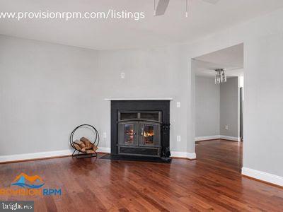1324 Hazel Nut Ct, Annapolis, MD 21409 - unfurnished living room featuring wood finished floors, baseboards, a ceiling fan, a fireplace with flush hearth, and a chandelier