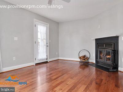 1324 Hazel Nut Ct, Annapolis, MD 21409 - unfurnished living room featuring a wood stove, baseboards, wood finished floors, and ceiling fan