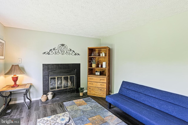 6786 Singletree Ct, Frederick, MD 21703 - living area with wood finished floors, a tiled fireplace, a textured ceiling, and baseboards