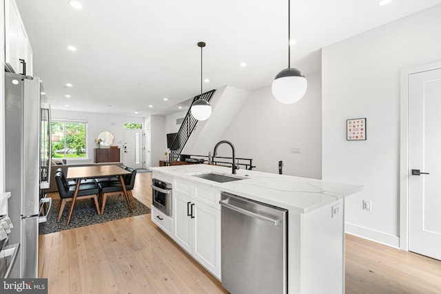 2206 E Fletcher St, Philadelphia, PA 19125 - kitchen featuring stainless steel appliances, a sink, light wood-style flooring, white cabinetry, and an island with sink
