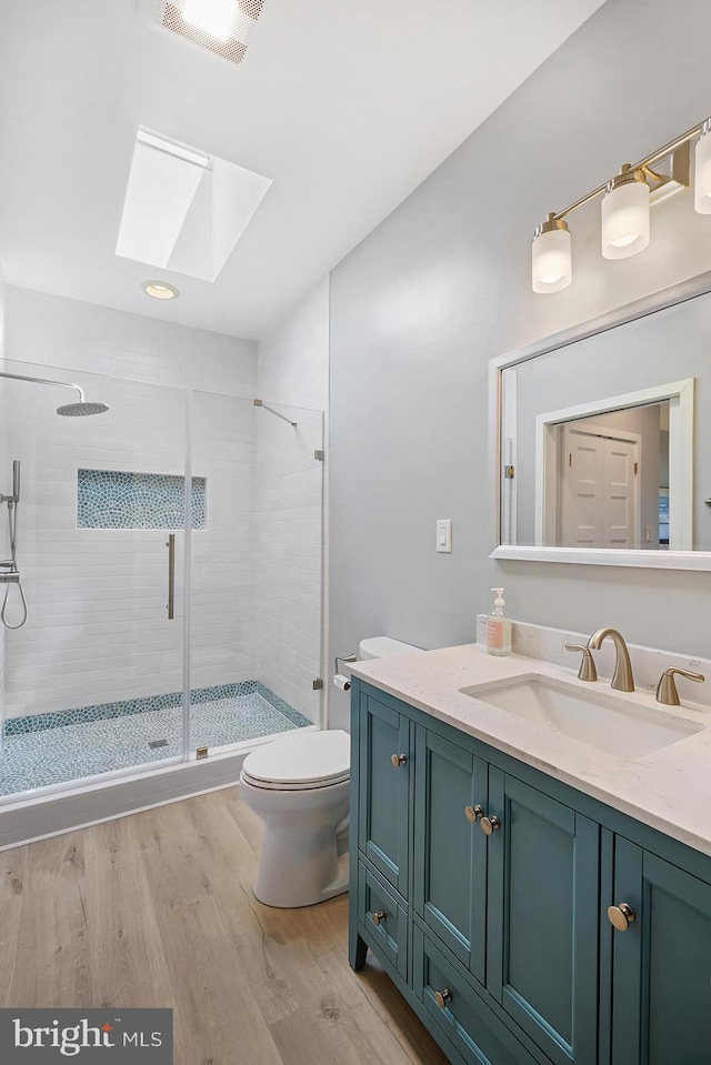 3442 Rockway Ave, Annapolis, MD 21403 - bathroom featuring a skylight, toilet, vanity, a stall shower, and wood finished floors