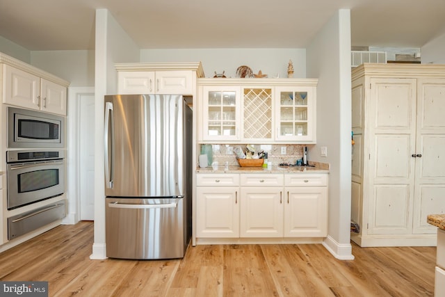 1107 Ocean Ave, Brigantine, NJ 08203 - kitchen featuring stainless steel appliances, a warming drawer, tasteful backsplash, glass insert cabinets, and light stone counters
