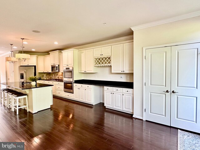 6967 Country Club Ter, New Market, MD 21774 - kitchen featuring stainless steel appliances, ornamental molding, dark countertops, dark wood-type flooring, and a kitchen bar