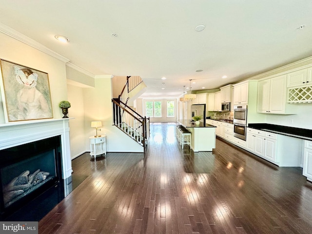 6967 Country Club Ter, New Market, MD 21774 - kitchen featuring dark countertops, appliances with stainless steel finishes, a breakfast bar, dark wood finished floors, and a fireplace