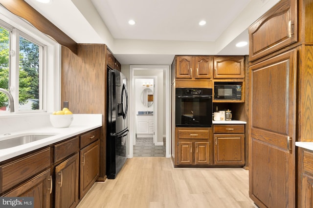 5404 Nedra Ave, Alexandria, VA 22310 - kitchen featuring black appliances, a sink, light wood-style floors, light countertops, and brown cabinetry