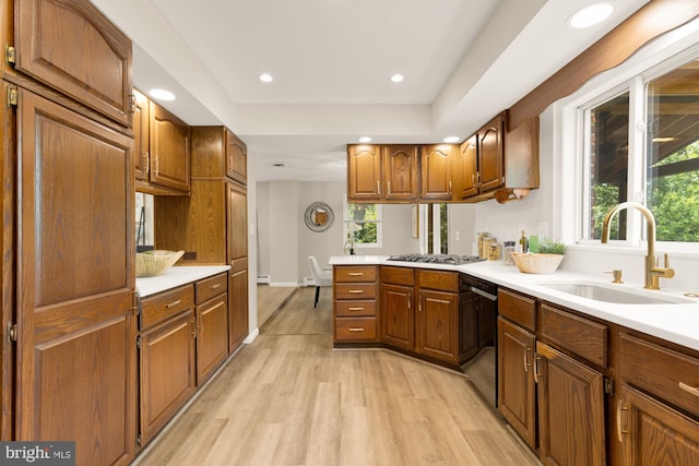 5404 Nedra Ave, Alexandria, VA 22310 - kitchen featuring a sink, light countertops, light wood-style floors, brown cabinetry, and plenty of natural light
