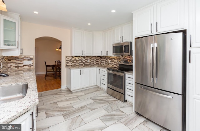 921 Coopertown Rd, Bryn Mawr, PA 19010 - kitchen with stainless steel appliances, arched walkways, a sink, tasteful backsplash, and light stone counters