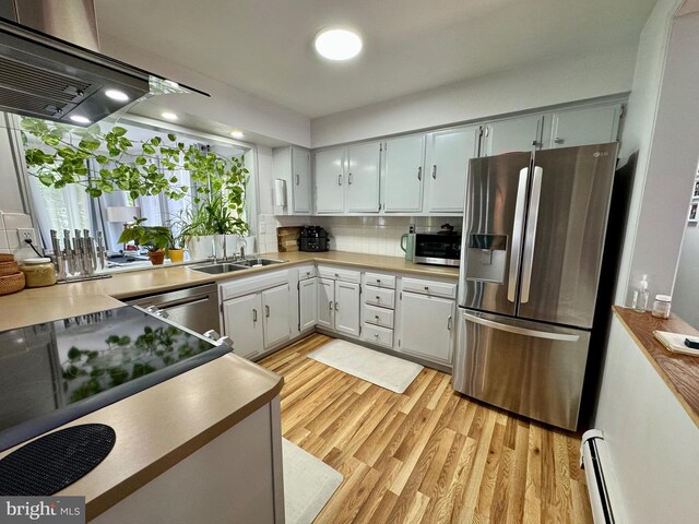 701 25th St, Huntingdon, PA 16652 - kitchen with stainless steel appliances, a sink, a baseboard heating unit, light wood finished floors, and tasteful backsplash