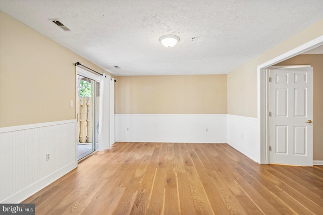 205 Quiet Ridge Ct, Pasadena, MD 21122 - unfurnished room featuring light wood-style floors, a wainscoted wall, a textured ceiling, and fire sprinkler in ceiling