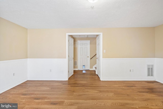 205 Quiet Ridge Ct, Pasadena, MD 21122 - empty room with wainscoting, wood finished floors, a textured ceiling, and stairway