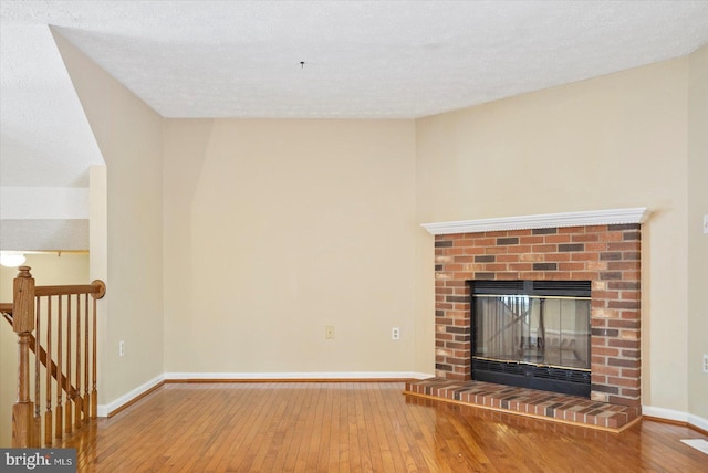 205 Quiet Ridge Ct, Pasadena, MD 21122 - unfurnished living room with hardwood / wood-style flooring, baseboards, a fireplace, and a textured ceiling