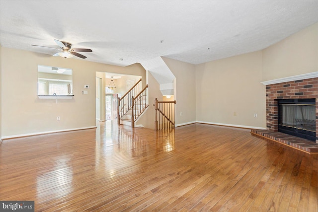 205 Quiet Ridge Ct, Pasadena, MD 21122 - unfurnished living room featuring wood-type flooring, stairs, a brick fireplace, a ceiling fan, and baseboards