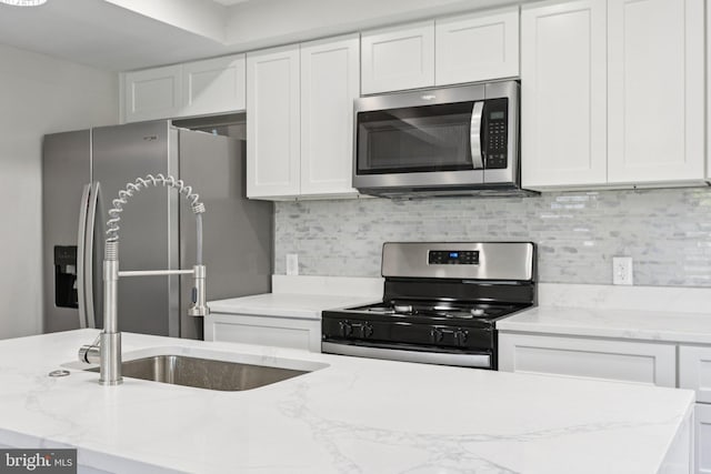 844 51st St NE, Washington, DC 20019 - kitchen with appliances with stainless steel finishes, white cabinets, decorative backsplash, and light stone counters