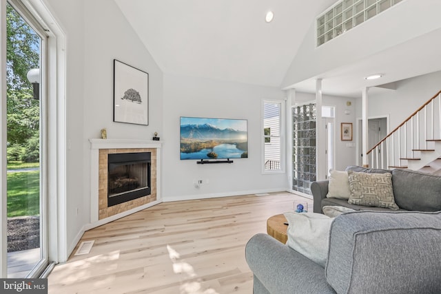 1012 Columbus Rd, Burlington, NJ 08016 - living room featuring wood finished floors, stairs, a tiled fireplace, baseboards, and high vaulted ceiling