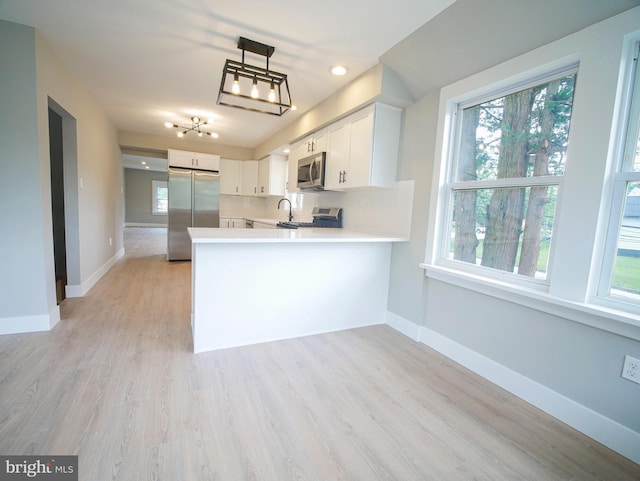 1200 First Ave, Media, PA 19063 - kitchen featuring appliances with stainless steel finishes, light countertops, a peninsula, white cabinetry, and healthy amount of natural light
