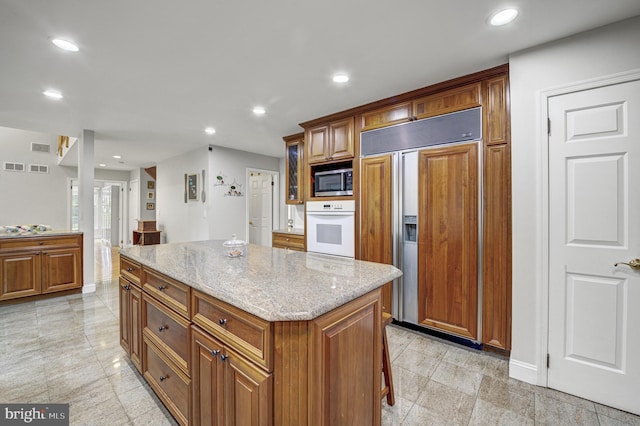3 Monroe Ct, Plainsboro, NJ 08536 - kitchen featuring built in appliances, brown cabinetry, a center island, light stone counters, and recessed lighting
