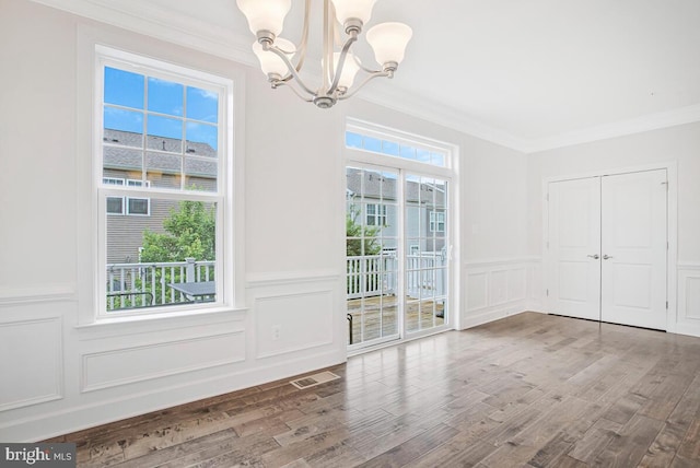 6911 Stansbury Ln, Landover, MD 20785 - unfurnished dining area featuring a chandelier, a decorative wall, plenty of natural light, ornamental molding, and wood finished floors
