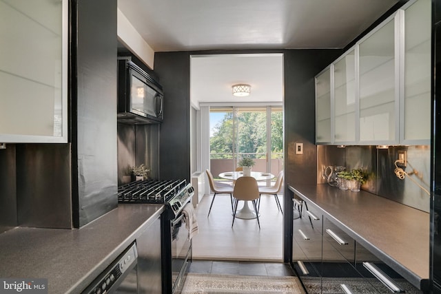 6631 Wakefield Dr Unit 209, Alexandria, VA 22307 - kitchen with black appliances, dark countertops, decorative backsplash, glass insert cabinets, and white cabinets
