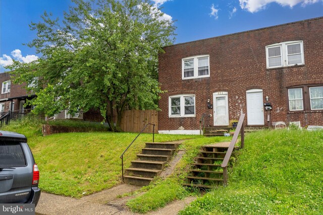 821 E Jeffrey St, Baltimore, MD 21225 - view of property with brick siding, a front yard, and stairway