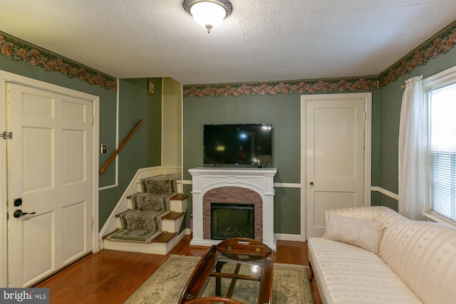 417 E Washington St, Charles Town, WV 25414 - living room featuring wood finished floors, stairs, a textured ceiling, and a fireplace with raised hearth