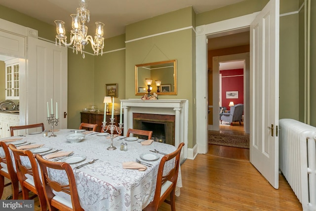 417 E Washington St, Charles Town, WV 25414 - dining space featuring radiator heating unit, light wood-type flooring, a chandelier, and a fireplace