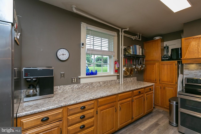 417 E Washington St, Charles Town, WV 25414 - kitchen featuring double oven range, wood finished floors, brown cabinetry, and light stone counters