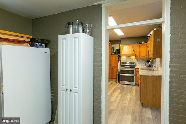 417 E Washington St, Charles Town, WV 25414 - kitchen featuring double oven range, light wood-style floors, freestanding refrigerator, decorative backsplash, and brown cabinetry