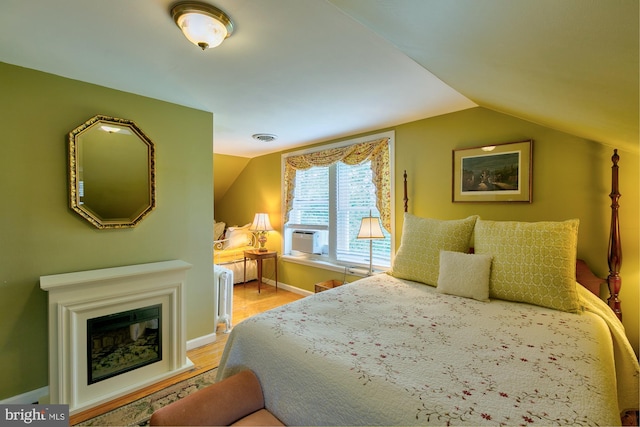 417 E Washington St, Charles Town, WV 25414 - bedroom featuring radiator heating unit, vaulted ceiling, light wood-type flooring, cooling unit, and a glass covered fireplace