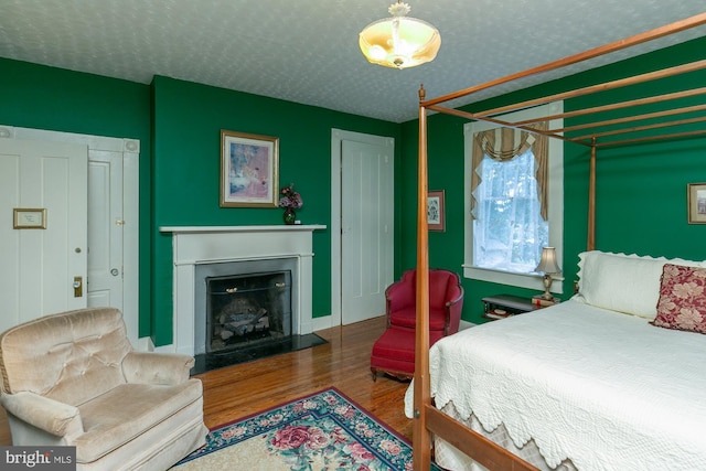 417 E Washington St, Charles Town, WV 25414 - bedroom with wood finished floors, a fireplace, and a textured ceiling