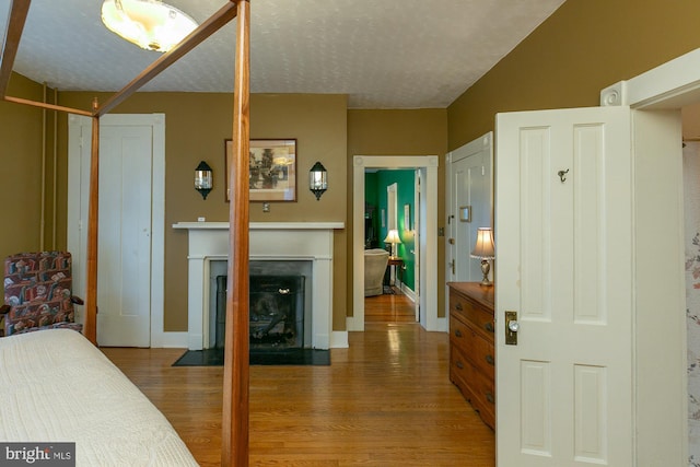 417 E Washington St, Charles Town, WV 25414 - bedroom with wood finished floors, a fireplace with flush hearth, and a textured ceiling