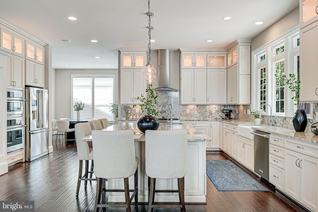 6513 Manor Ridge Ct, Falls Church, VA 22043 - kitchen featuring wall chimney range hood, stainless steel appliances, a sink, tasteful backsplash, and an island with sink