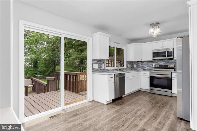 11239 Putman Rd, Thurmont, MD 21788 - kitchen with appliances with stainless steel finishes, light countertops, tasteful backsplash, light wood-style floors, and white cabinetry
