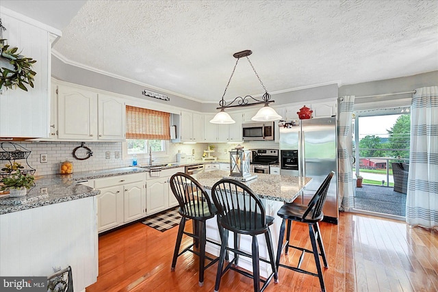 11 Thomas Cir, New Freedom, PA 17349 - kitchen with appliances with stainless steel finishes, plenty of natural light, white cabinetry, light wood-style floors, and a textured ceiling