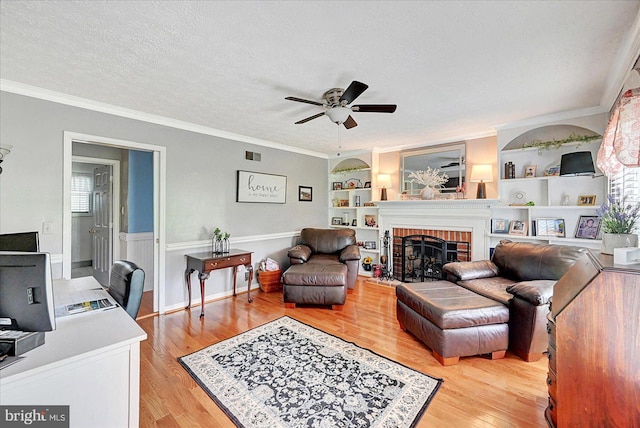 11 Thomas Cir, New Freedom, PA 17349 - living room with ceiling fan, light wood-style flooring, crown molding, a brick fireplace, and a textured ceiling