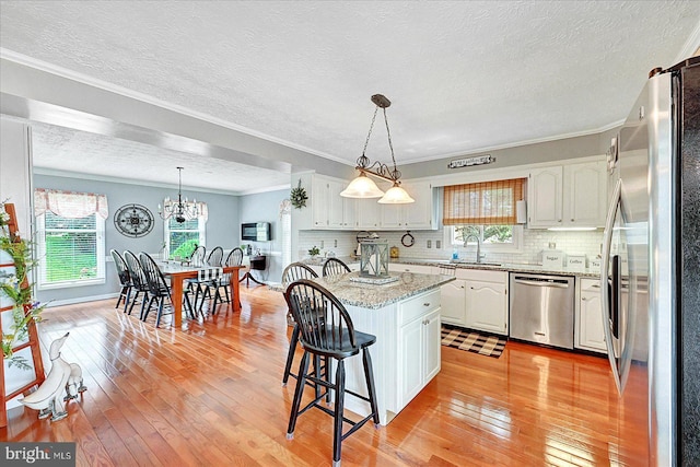 11 Thomas Cir, New Freedom, PA 17349 - kitchen with appliances with stainless steel finishes, white cabinetry, light wood-type flooring, a textured ceiling, and a kitchen breakfast bar