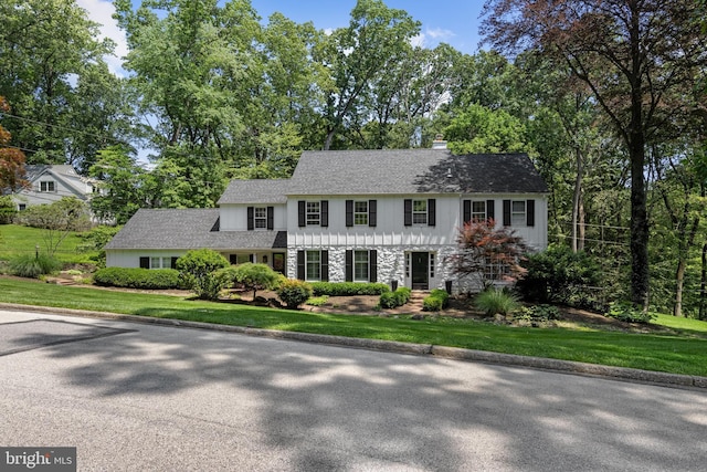 661 Timber Ln, Devon, PA 19333 - view of front facade featuring stone siding, a front lawn, a chimney, roof with shingles, and view of scattered trees