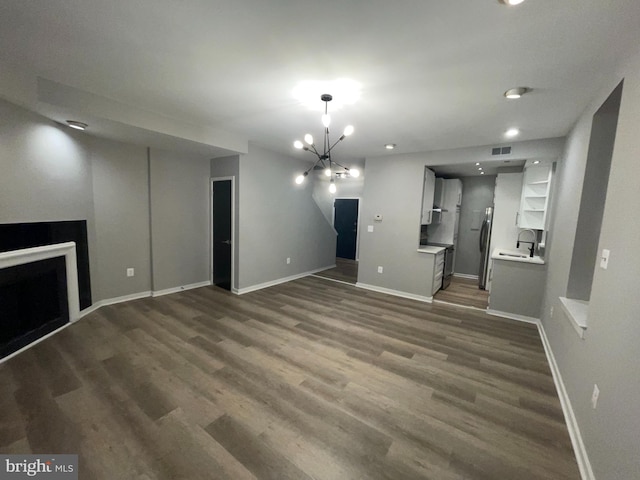 1742 U St NW Unit 203, Washington, DC 20009 - unfurnished living room featuring baseboards, a chandelier, dark wood-type flooring, a sink, and a fireplace