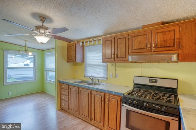32588 Captains Way, Millsboro, DE 19966 - kitchen featuring stainless steel range with gas cooktop, a sink, wall chimney exhaust hood, a textured ceiling, and brown cabinets