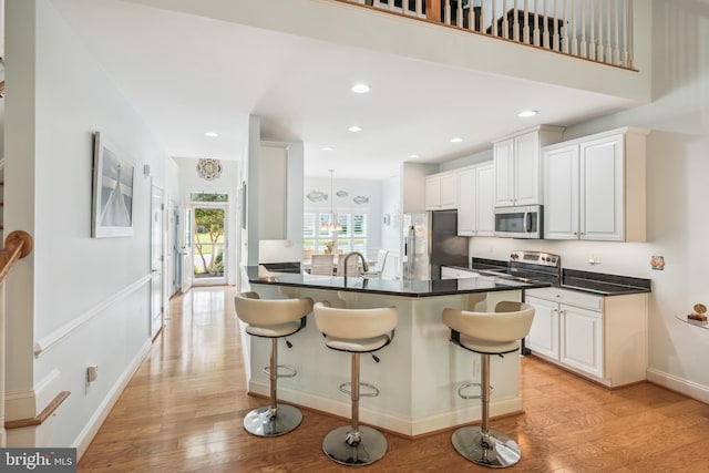 36769 E Pebble Beach Dr, Frankford, DE 19945 - kitchen featuring appliances with stainless steel finishes, light wood finished floors, a breakfast bar, dark countertops, and recessed lighting