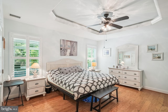 36769 E Pebble Beach Dr, Frankford, DE 19945 - bedroom featuring a tray ceiling, multiple windows, light wood-style floors, and a ceiling fan