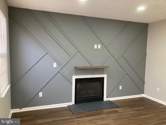 9831 Endora Ct, Owings Mills, MD 21117 - detailed view of a decorative wall, baseboards, wood finished floors, a fireplace with raised hearth, and recessed lighting