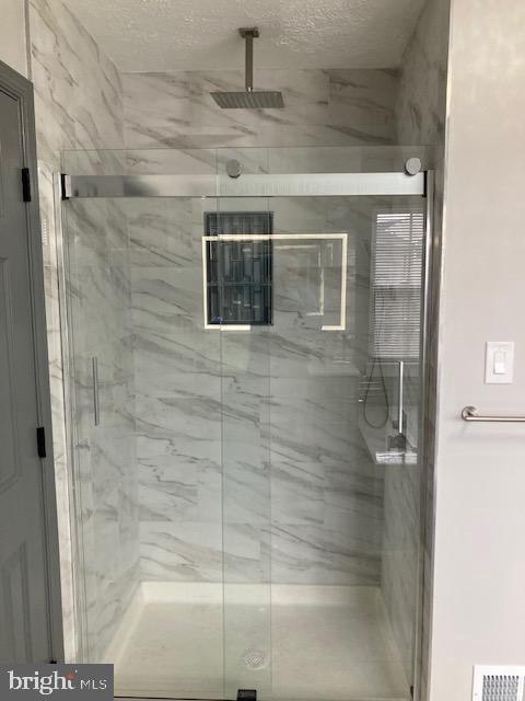 9831 Endora Ct, Owings Mills, MD 21117 - bathroom featuring a marble finish shower and a textured ceiling