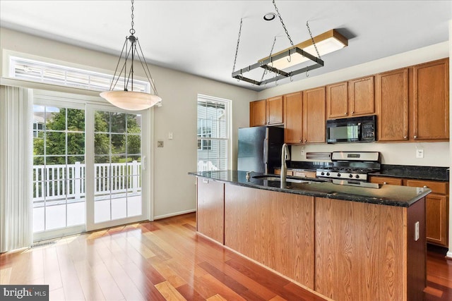 916 E Fox Hound Chase Chase, Glen Mills, PA 19342 - kitchen with black microwave, stainless steel range with gas cooktop, freestanding refrigerator, light wood finished floors, and brown cabinets