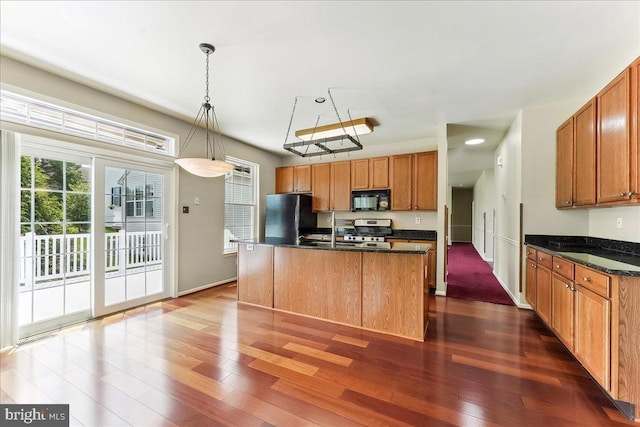 916 E Fox Hound Chase Chase, Glen Mills, PA 19342 - kitchen featuring freestanding refrigerator, black microwave, dark wood finished floors, stainless steel range with gas stovetop, and a center island with sink