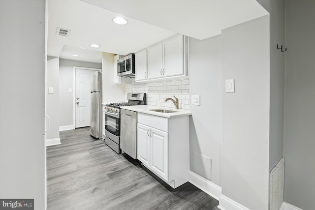 329 S Durham St, Baltimore, MD 21231 - kitchen featuring appliances with stainless steel finishes, a sink, baseboards, white cabinets, and light wood finished floors