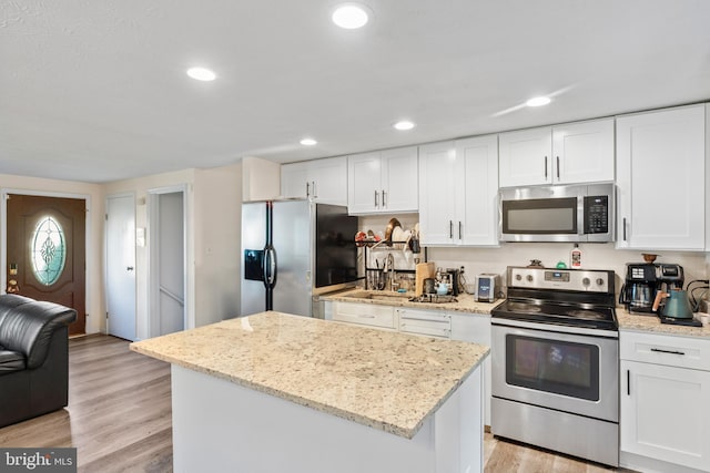 7627 Fallswood Way, Lorton, VA 22079 - kitchen with appliances with stainless steel finishes, white cabinets, a center island, light stone countertops, and recessed lighting